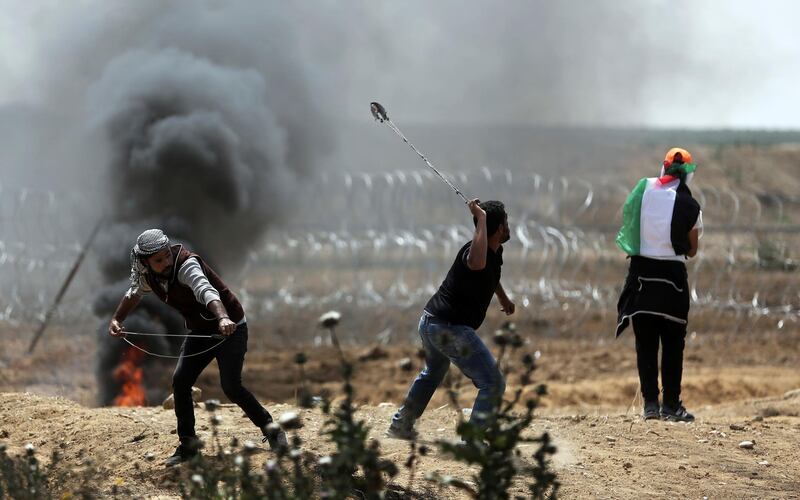 Palestinian protesters hurl stones at Israeli troops during a protest at the Gaza Strip's border with Israel. Khalil Hamra / Ap Photo