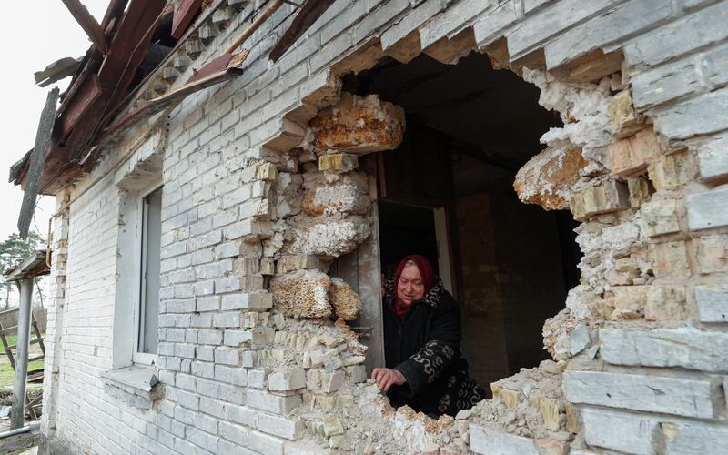 Nadiya, 65, shows a hole in a wall of a building after shelling in Zalissya, Ukraine. EPA