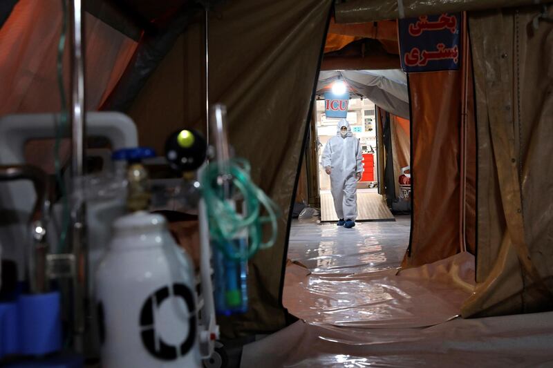 A person in protective clothing walks through a temporary 2,000-bed hospital for COVID-19 coronavirus patients. AP Photo