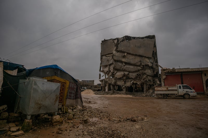 A family's tent pitched near a precarious ruined building in Jindires. An estimated 1.5 million people were left homeless in Syria and Turkey