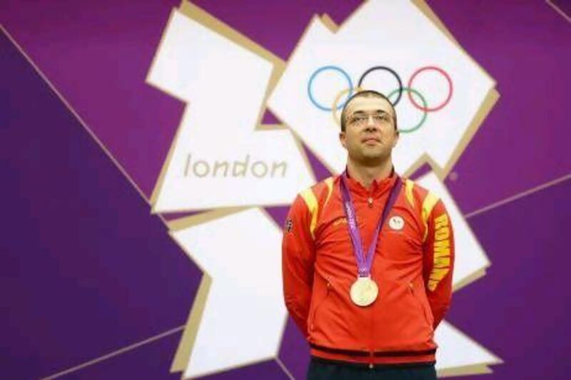 Alin George Moldoveanu of Romania poses on the podium with the gold medal won in the men's 10m air rifle shooting final.