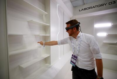 FILE PHOTO: A gamer grabs for a virtual book from an empty shelf as he wears augmented reality goggles during the media day of Europe's leading digital games fair Gamescom, which showcases the latest trends of the computer gaming scene, in Cologne, Germany, August 20, 2019. REUTERS/Wolfgang Rattay/File Photo