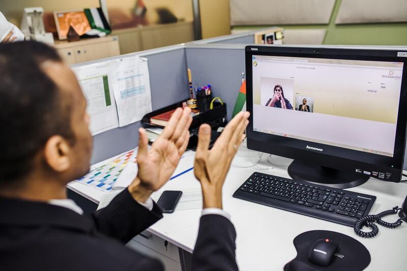 A Sanad Relay Centre interpreter talks with an executive at Dubai Immigration Authority who is hearing impaired. Alex Atack for The National