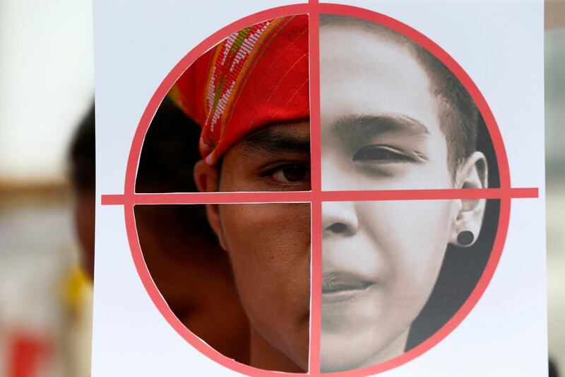 A Filipino communist protester peers from behind a cutout showing a portrait of a communist activist killed during a recent demonstration in Manila. The recent protest was in response to Philippine president Rodrigo Duterte's formally declaring the Communist Party of the Philippines and its armed wing, the New People's Army, are a terrorist organisation.  Bullit Marquez / AP Photo