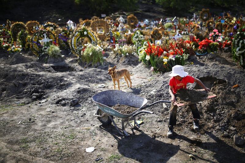 Jesus, a boy who works with his father cleaning and decorating graves, loads land on a wheelbarrow at the Xico cemetery on the outskirts of Mexico City.. Reuters