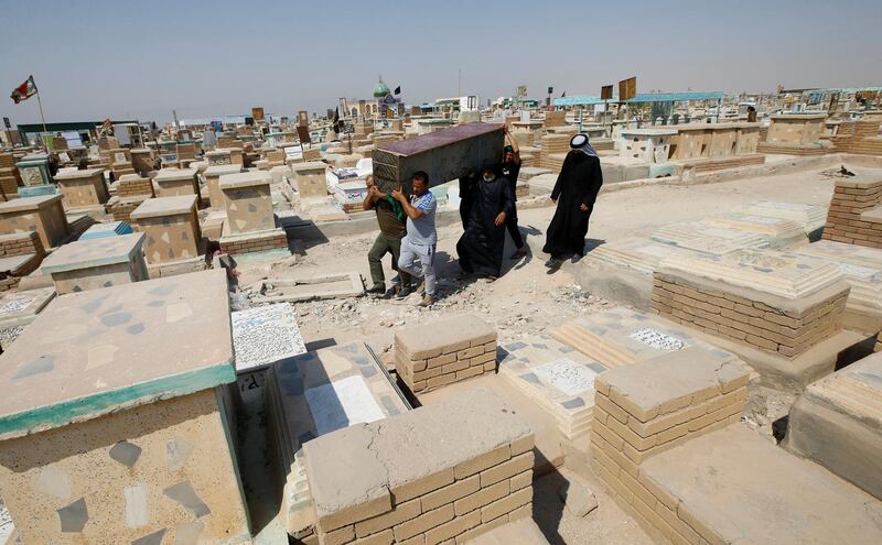 Iraqi men rebury a relative who was laid to rest in a cemetery dedicated to those who died of Covid-19 at the 'Valley of Peace' cemetery, in the city of Najaf, Iraq. Reuters