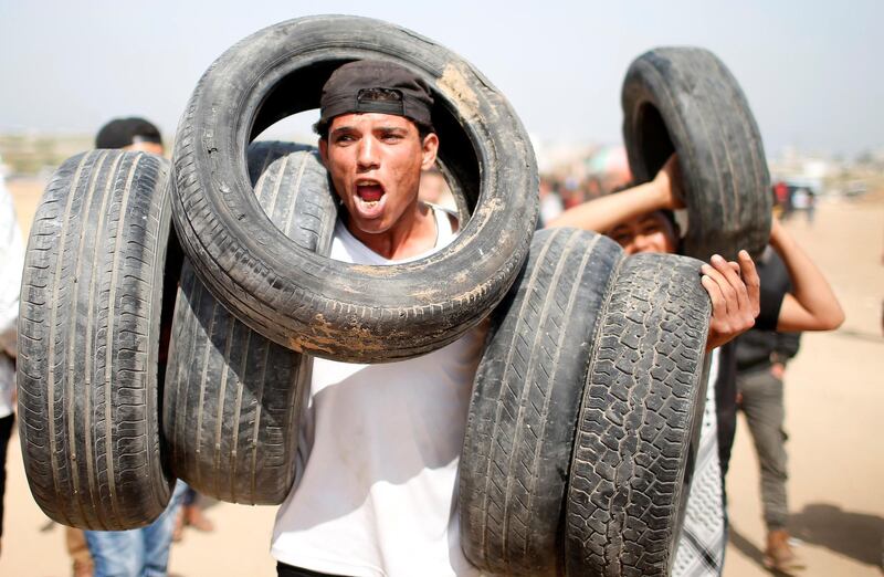 A Palestinian youth carries tyres that protesters were setting on fire on the Israel-Gaza border. Reuters
