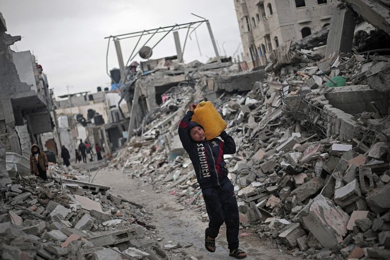 A Palestinian boy carries a water container amid the rubble of houses destroyed by Israeli bombardment in Rafah in the southern Gaza Strip. AFP