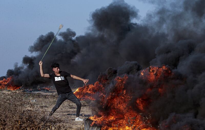 A Palestinian protester throws stones at Israeli troops during clashes on the eastern border of the Gaza Strip, on Friday. EPA
