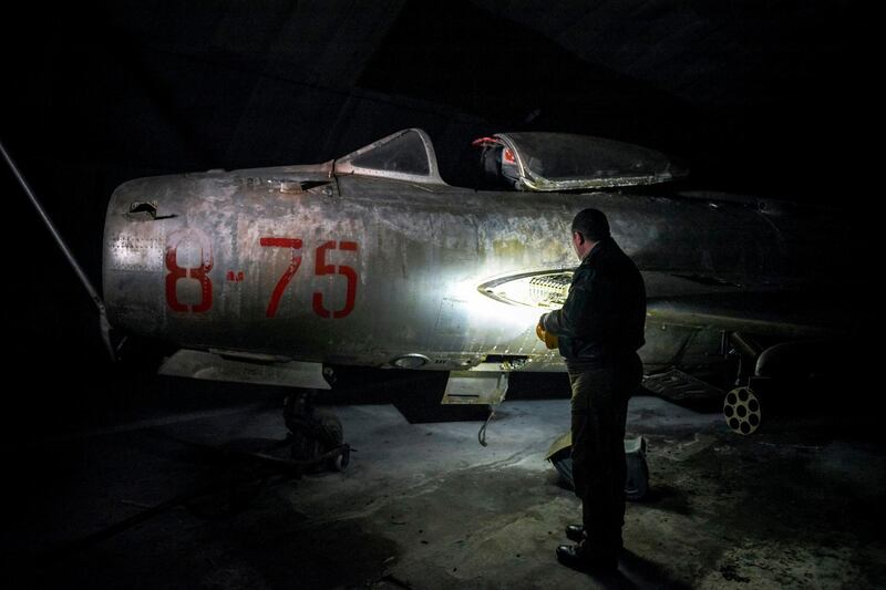 Albanian fighter jet pilot and former airforce commander Fatmir Danaj, 52, inspects a MiG-19 jet fighter inside the main tunnel of the Gjader Air Base built near the city of Lezhe, on February 5, 2019. On a barren hillside in northern Albania lies a portal to the country's communist past: a massive steel door creaks open to reveal a hidden former air base burrowed into the heart of the mountain. Made up of 600 metres (1,980 feet) of tunnels that once teemed with military life, the secret Gjader air base is now a depot for dozens of hulking communist-era MiG jets collecting dust in the darkness. Three decades after shedding communism, Albanian authorities are still trying to sell off the Soviet and Chinese-made aircraft, of which there are dozens more in another nearby air base.
 / AFP / Gent SHKULLAKU
