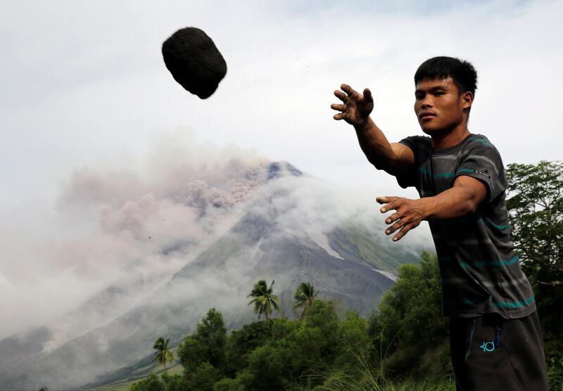 A Filipino villager collects rocks along the slopes of rumbling Mayon Volcano as it spews ash in Legaspi city, Albay province in the Philippines. Francis R. Malasig / EPA
