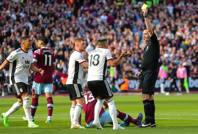 Referee Chris Kavanagh shows Andreas Pereira a yellow card after the Fulham player gave away a penalty for fouling West Ham defender Craig Dawson. PA