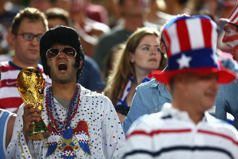 A United States fan dressed as Elvis holds up a replica of the World Cup trophy. Michael Steele / Getty Images