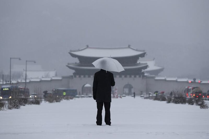 A man uses an umbrella on January 20, 2017 against the snow near the Gwanghwamun — the main gate of the 14th-century Gyeongbok Palace — a South Korea landmark, in Seoul. Lee Jin-man / Associated Press