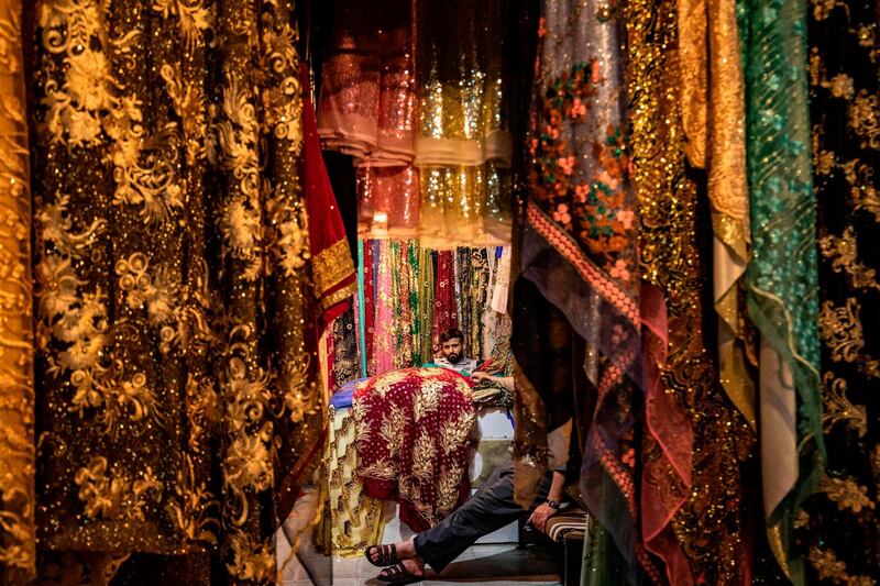 A shopkeeper sits with a friend inside his textile shop at the main market of the Kurdish-majority city of Qamishli in Syria's northeastern Hasakeh province on May 19, 2020, ahead of the upcoming Muslim holiday of Eid al-Fitr celebrated at the conclusion of the holy fasting month of Ramadan.  / AFP / DELIL SOULEIMAN
