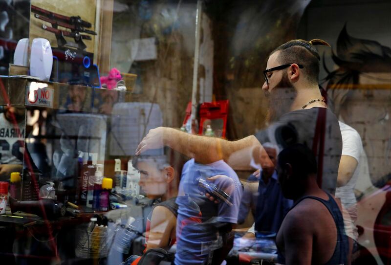 
                  In this Friday, July 14, 2017 photo shot through a window, Muhannad Khaled Omar, right, prepares to create an image of U.S. President Donald Trump on the back of a customer's head at his barber shop in Burj al-Barajneh, southern Beirut, Lebanon. In a city full of hair stylists, Omar stands out. He is a 26 year-old Palestinian-Syrian hair stylist known for shaving celebrity portraits into clients’ hair. (AP Photo/Bilal Hussein)
               