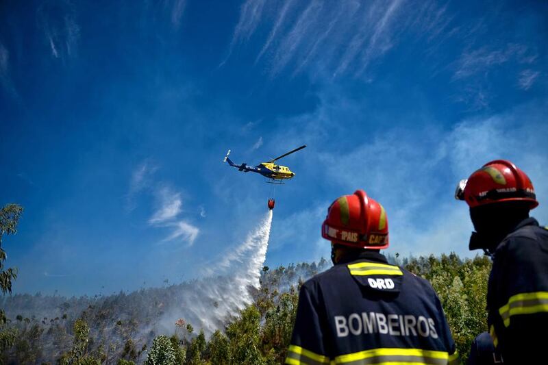 Firefighters watch a helicopter dropping water on a wildfire at Monchique, Algarve, southern of Portugal. Patricia De Melo Moreira / AFP