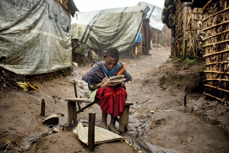 Portrait of a 12 years old girl in Katale IDP Camp in Masisi territory. She does her homework during the last daylight hours in front of her hut.