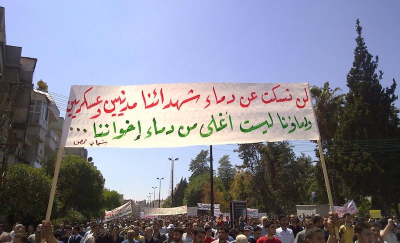 Syrian anti-government protesters in May 2011 carry a banner that reads in Arabic: ”Our blood is not more precious than the blood of our brothers, the youth of Homs” during a rally in the central city of Homs. AP Photo