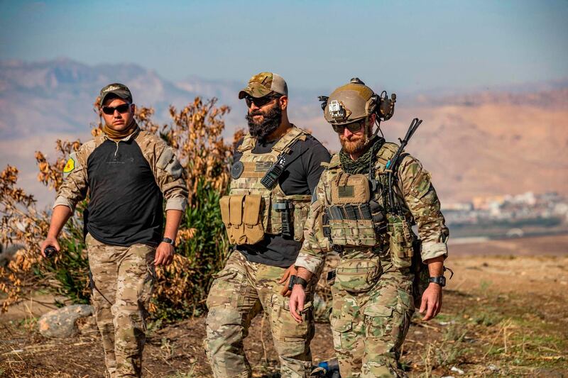 (L to R) A member of the Kurdish People's Protection Units (YPG) walks with US soldiers during a patrol in the village of Ein Diwar in Syria's northeastern Hasakeh province.  AFP