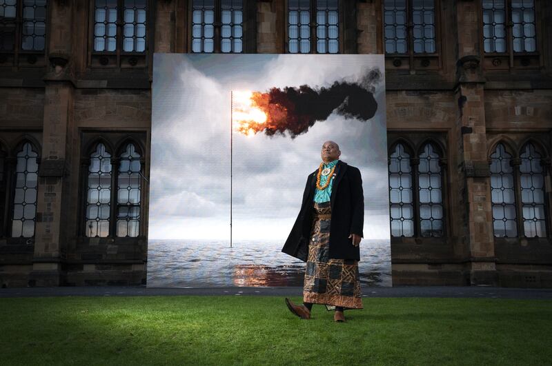 Tongan artist and activist Uili Lousi stands alongside 'Flare (Oceania) 2021', created by Irish artist John Gerrard. The real-time moving image shows a simulation of the seas around Tonga. PA