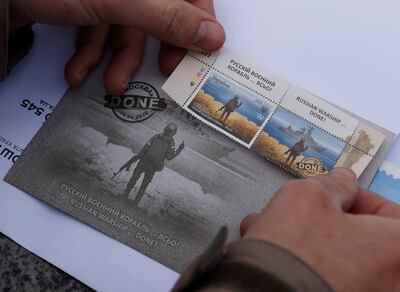 A man pastes a new series of commemorative Snake Island anti-Russian stamps on a postcard, amid the Russian invasion of Ukraine, outside the post office in Kyiv. Reuters