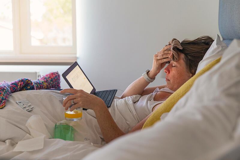 Woman suffering in bed with a fever and flu like symptoms. Getty Images