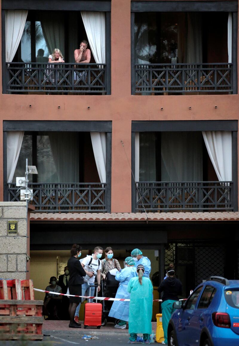 Health personnel wearing protection clothing check the temperature of a guest at the H10 Costa Adeje Palace hotel in La Caleta, in the Canary Island of Tenerife, Spain, Friday Feb. 28, 2020. Some guests have started to leave the locked down hotel after undergoing screening for the new virus that is infecting hundreds worldwide. (AP Photo/Joan Mateu)