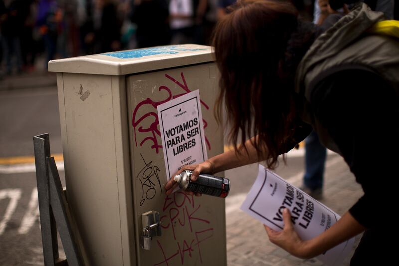 A pro independence supporter pastes a poster calling for voting Yes on a planned independence referendum in the Catalonia region, during a demonstration in Barcelona, Spain, Sunday, Sept. 17, 2017. The Spanish government has vowed to stop the planned Oct. 1 vote that it calls illegal. But Catalonia's leaders have pushed ahead even after Spain's Constitutional Court suspended the law passed by Catalonia's regional parliament that convoked the referendum. The poster in Spanish reads: "We are voting to get freedom". (AP Photo/Emilio Morenatti)