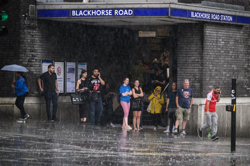 People take shelter in the entrance to an underground station, as torrential rain and thunderstorms hit London in 2022 Getty Images