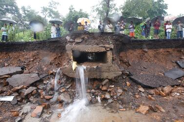 People stand at the spot after heavy rainfall caused a wall to collapse onto shanties, in Mumbai, India, Tuesday, July 2, 2019. AP