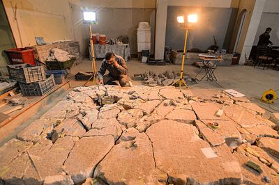 A worker at Mosul Museum tries to piece together broken fragments of an artefact that bore cuneiform inscriptions. AFP