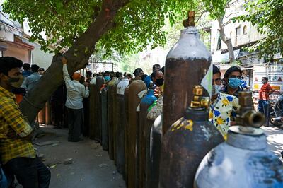 People wait in a line to refill oxygen cylinders for Covid-19 coronavirus patients at a refilling centre in New Delhi on May 5, 2021. / AFP / Tauseef MUSTAFA
