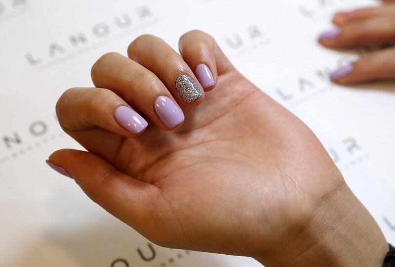 Customer showing the glitter nail with microchip at the Lanour Beauty Lounge in Duja tower in Dubai on June 22,2021. Lanour Beauty Lounge in Dubai is offering microchip manicures, which paint a microchip which can double as a business card under the nail. The idea came about as a covid-friendly way of sharing business cards. Pawan Singh / The National. Story by Gill