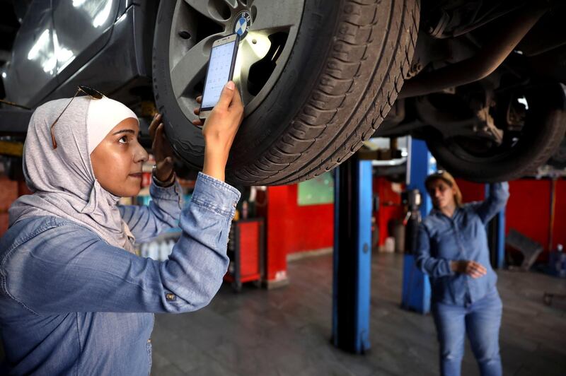 Jordanian female mechanics, Ahlam al Atayyar and Hiba al Juqa, check the car of one of their clients in Amman, Jordan.  Reuters