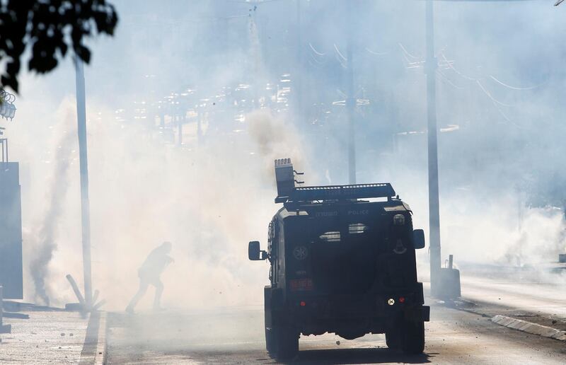 A Palestinian protester runs for cover from tear gas fired by Israeli troops. Mussa Qawasma / Reuters