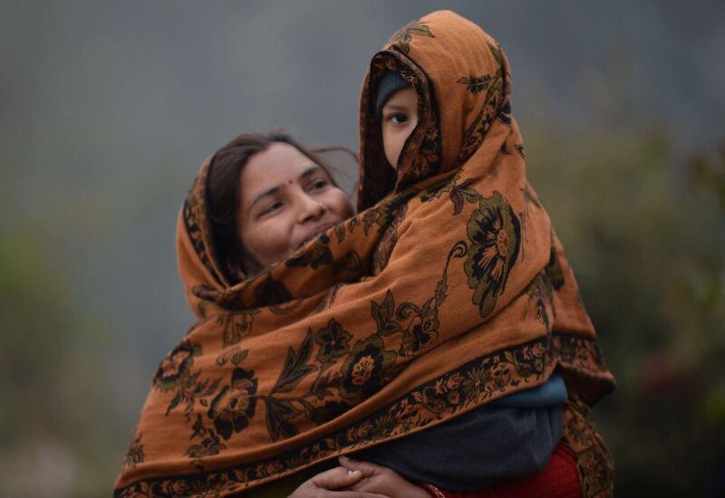 An Indian woman carries her son to school wrapped in a shawl on a cold foggy morning in New Delhi, India. Prakash Singh / AFP