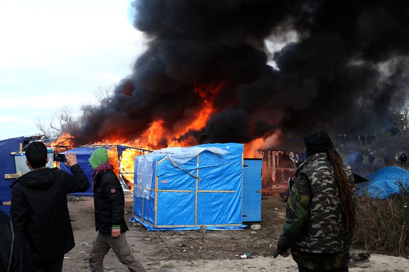 A hut burns as police officers clear part of the camp in February 2016