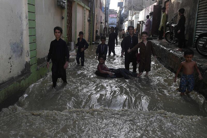 Children play on a waterlogged alley after heavy monsoon rains in Karachi. AFP