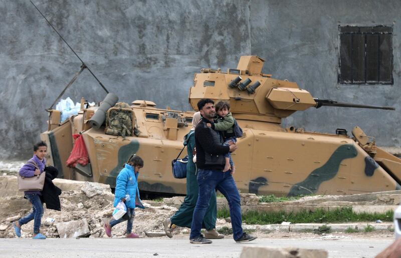 A family walks past a military vehicle belonging to Turkish-backed Free Syrian Army fighters after the capture of Khaldieh village, in eastern Afrin, Syria on March 10, 2018. Khalil Ashawi / Reuters