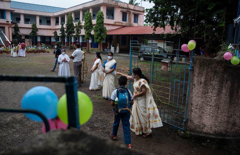 A teacher guides a pupil to his classroom. Schools in this southern state were closed for nearly 20 months due to the coronavirus pandemic.