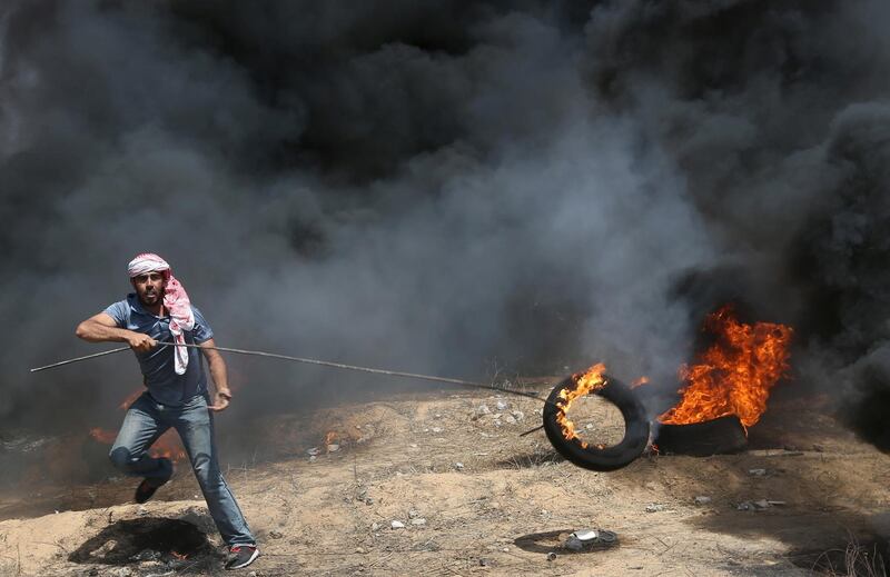 A demonstrator drags along a burning tyre.  Ibraheem Abu Mustafa / Reuters
