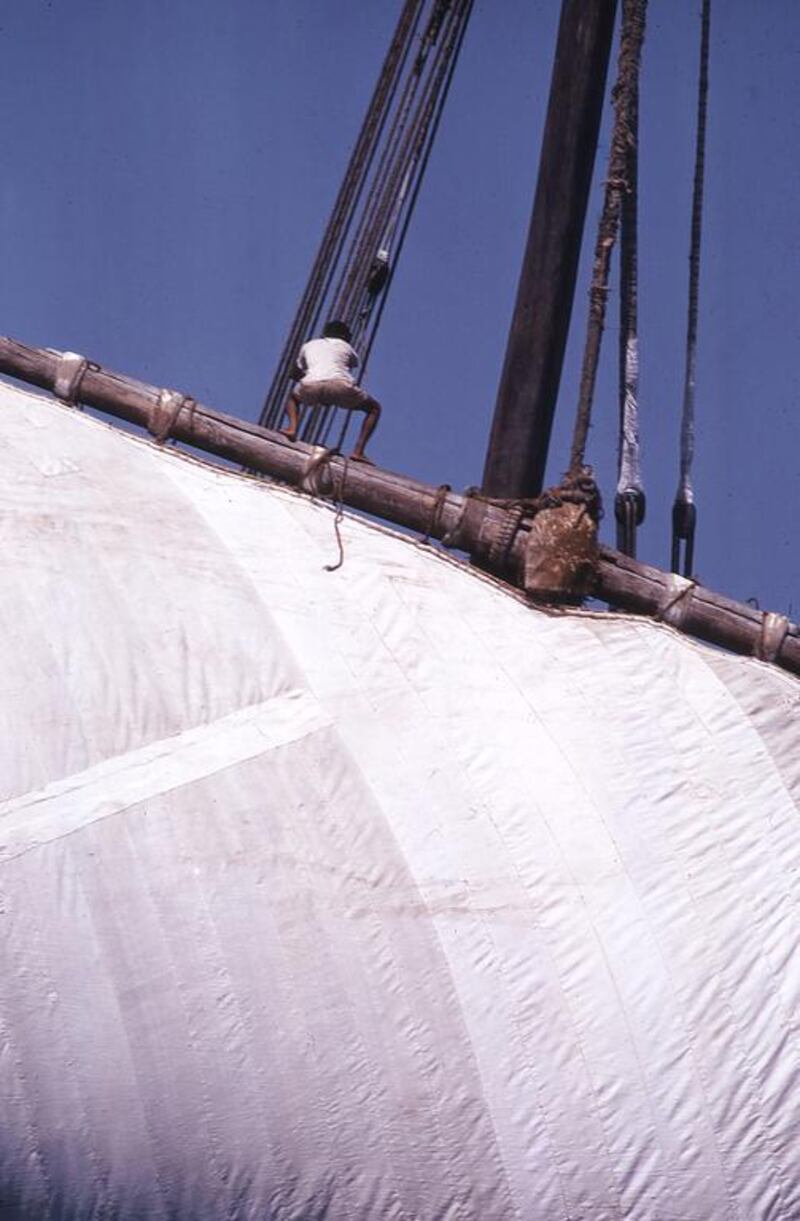 A crew member helps raise the sail.