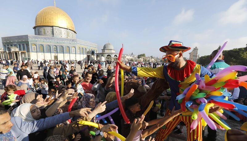 A clown distributes balloons near the Dome of the Rock at al-Aqsa Mosque compound in Jerusalem's old city on the first day of Eid Al Adha. AFP