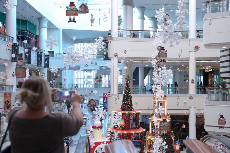 A shopper takes photos of the centre atrium Christmas decoration at Al Wahda Mall, Abu Dhabi. Khushnum Bhandari / The National