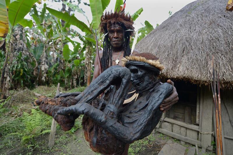 Tribe chief Eli Mabel poses with the mummified remains of his ancestor, Agat Mamete Mabel, outside a traditional house in the village of Wogi in Wamena, the long-isolated home of the Dani tribe high in the Papuan central highlands. Adek Berry/AFP