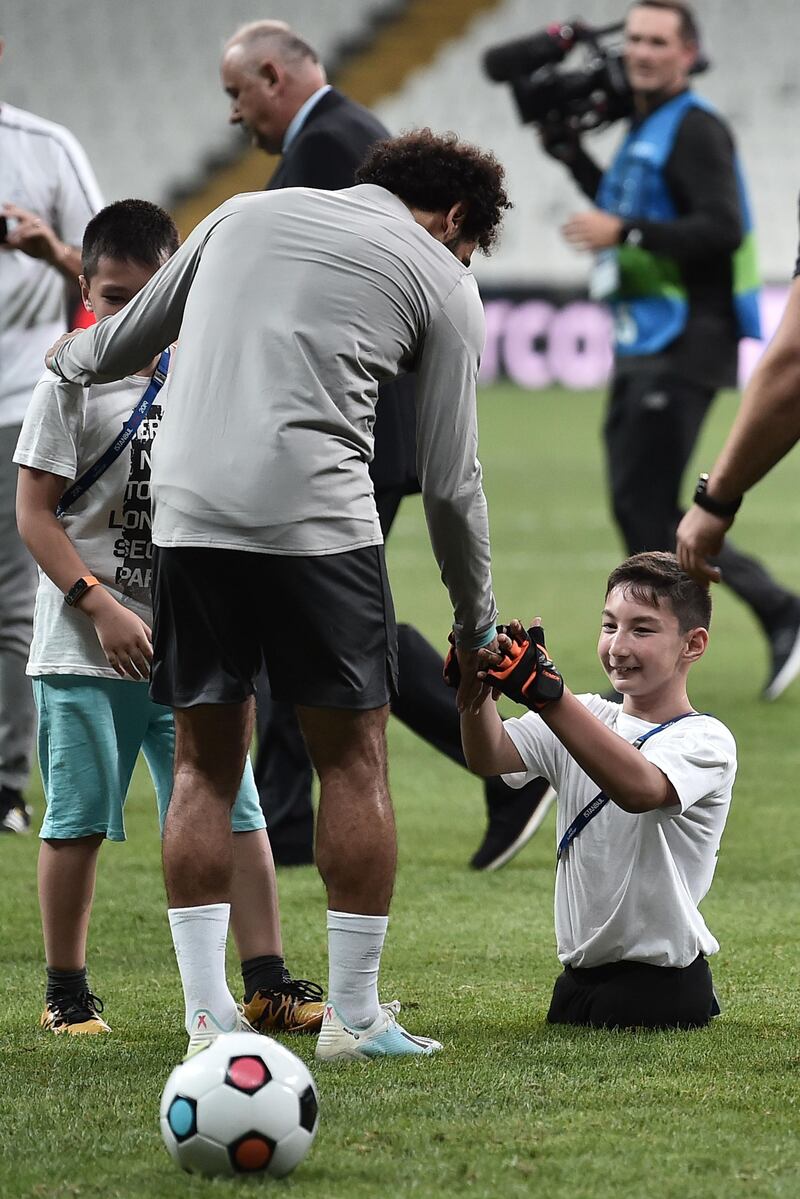 Mohamed Salah plays football with a child at the end of a training session. AFP