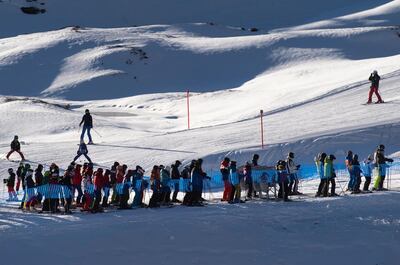 FILE - In this Sunday, Nov. 29, 2020 file photo ski enthusiasts with protective face masks queue for the ski lift, in Arosa, Switzerland.  Swiss ski stations that has become an epicenter of discord among Alpine neighbors. EU member states Austria, France, Germany and Italy are shutting or severely restricting access to the slopes this holiday season amid COVID-19 concerns, Switzerland is not.   (Gian Ehrenzeller/Keystone via AP, File)