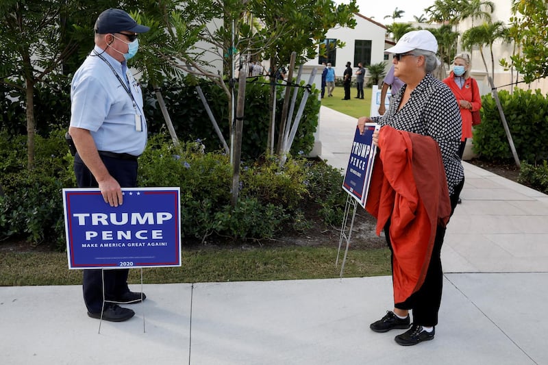 A Code Enforcement officer asks to a supporter to stop placing US President Donald Trump and Vice President Mike Pence campaign signs in the limits of a polling station during the 2020 US presidential election in Palm Beach, Florida. Reuters