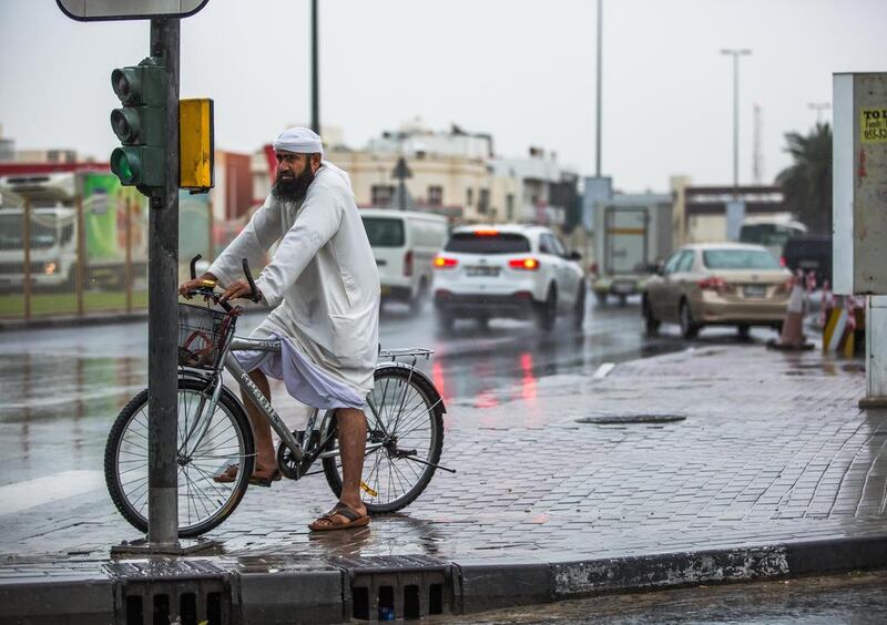 A man waits to cross the road during severe rain in Dubai. Victor Besa for The National